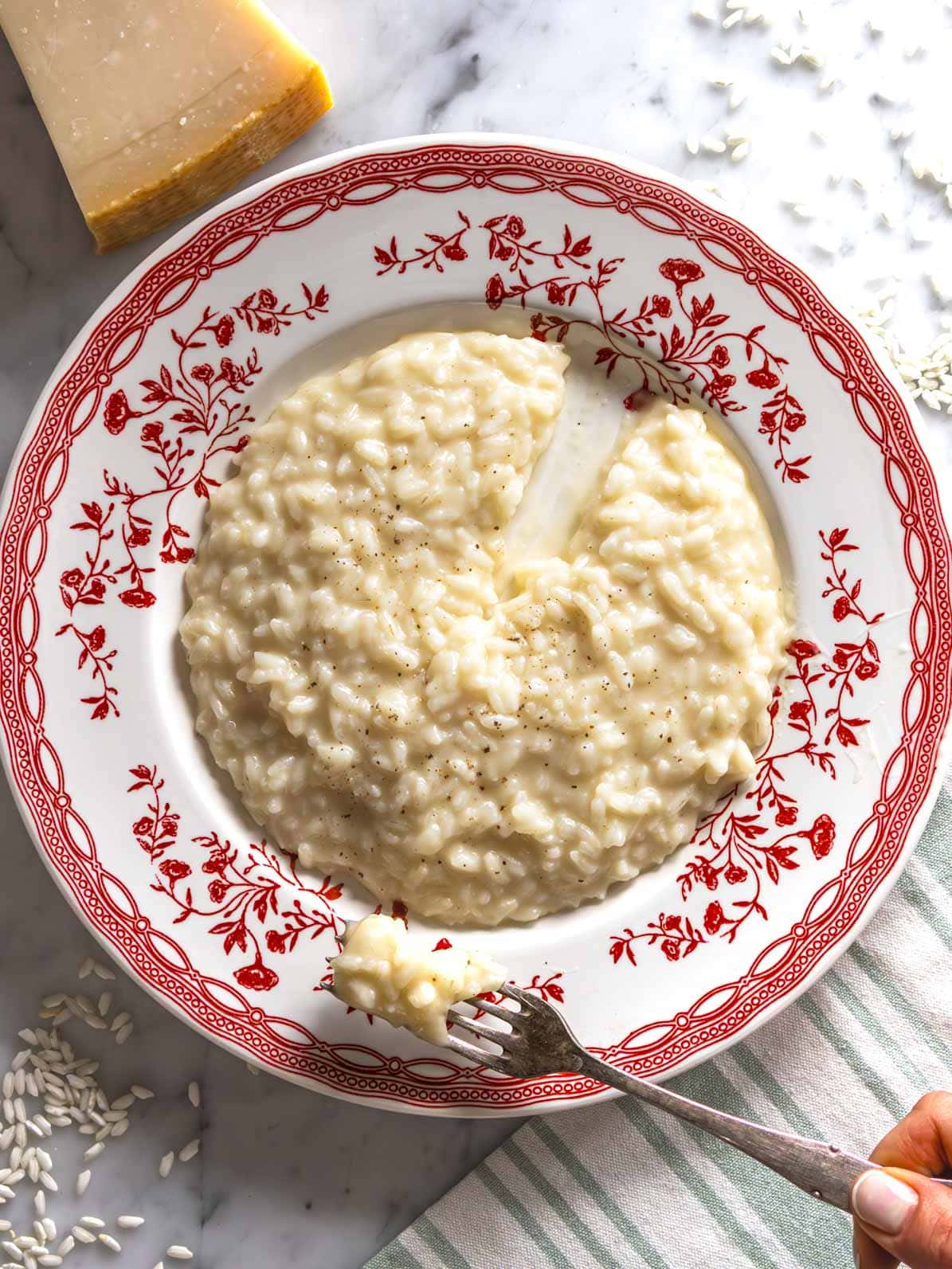Parmesan risotto with female hand holding a fork.