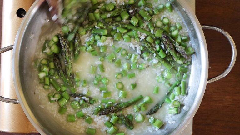 cooking the vegan risotto with vegetable broth and asparagus