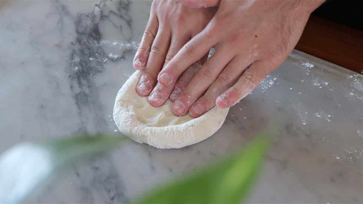flattening dough with hands