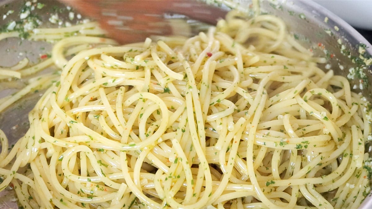 cooking the spaghetti in the aglio e olio sauce