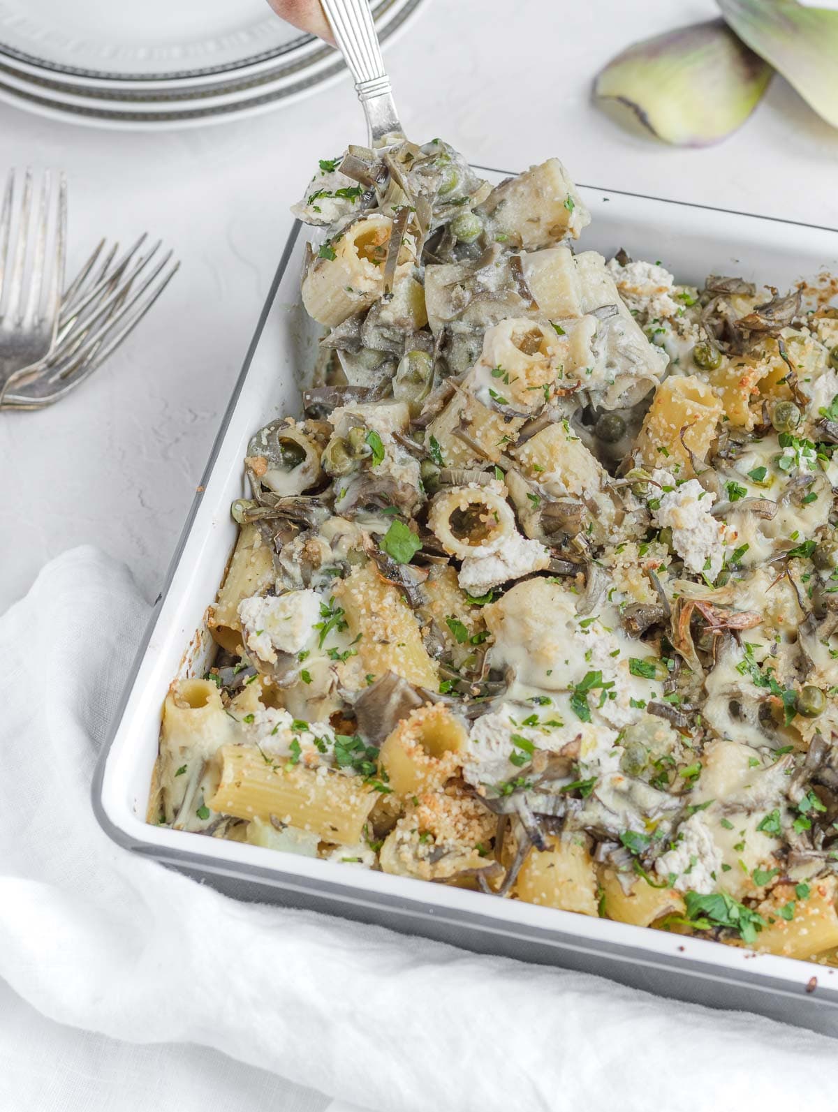 artichoke pasta bake with a big spoon ready to be served.