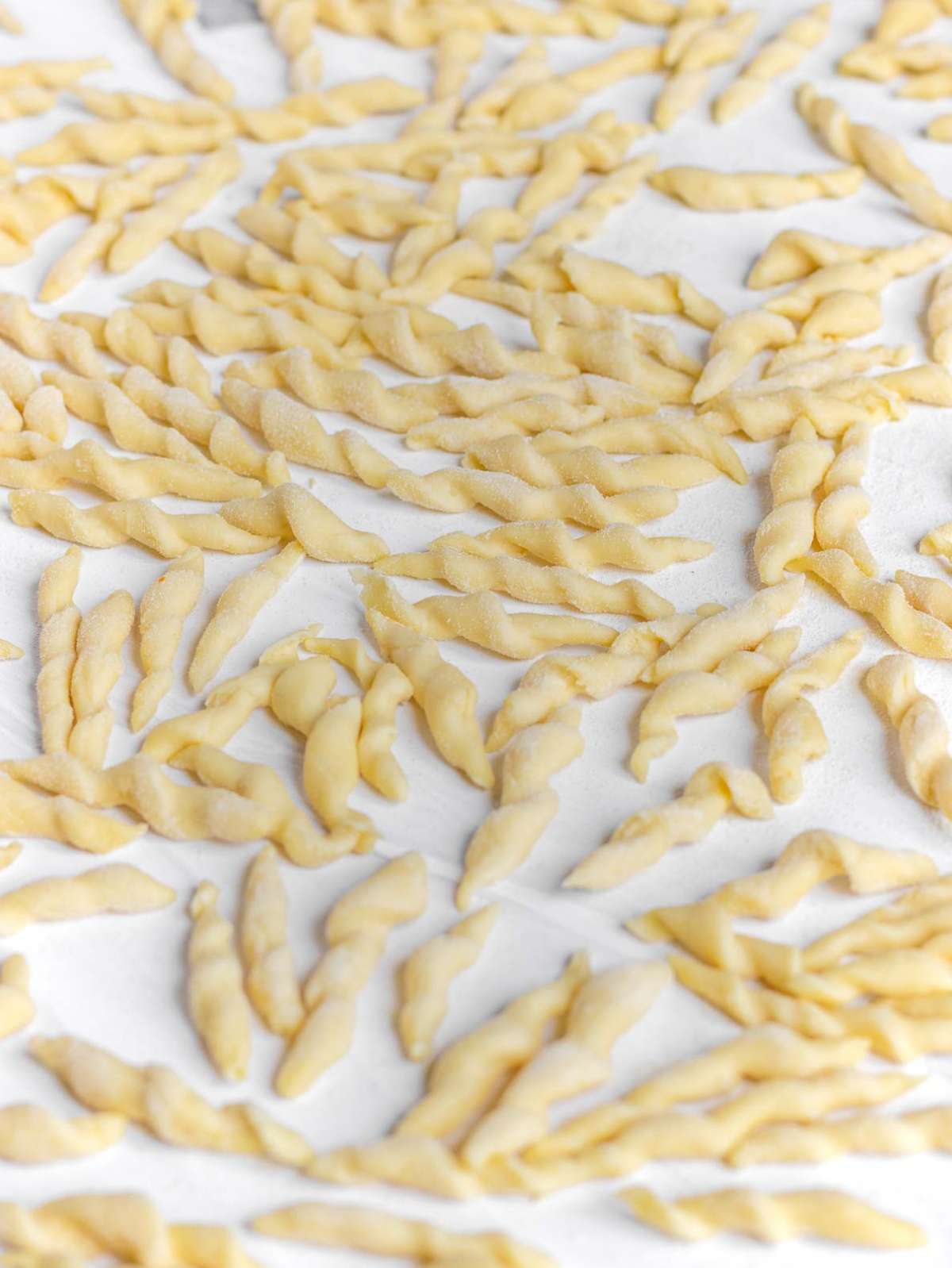 Close up of homemade trofie pasta drying on a worktop.