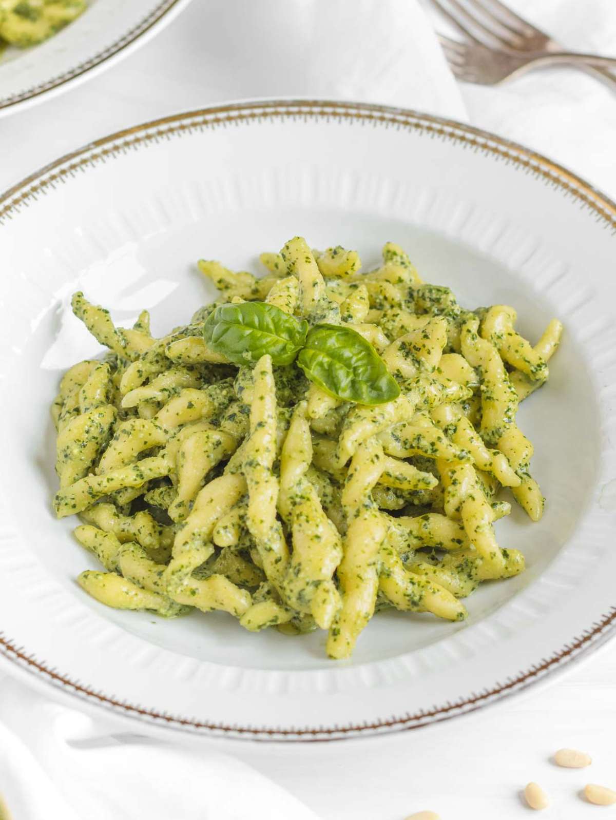 Homemade trofie pasta served with pesto alla Genovese on a white plate.