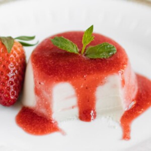 close up dairy free panna cotta with dripping strawberry sauce