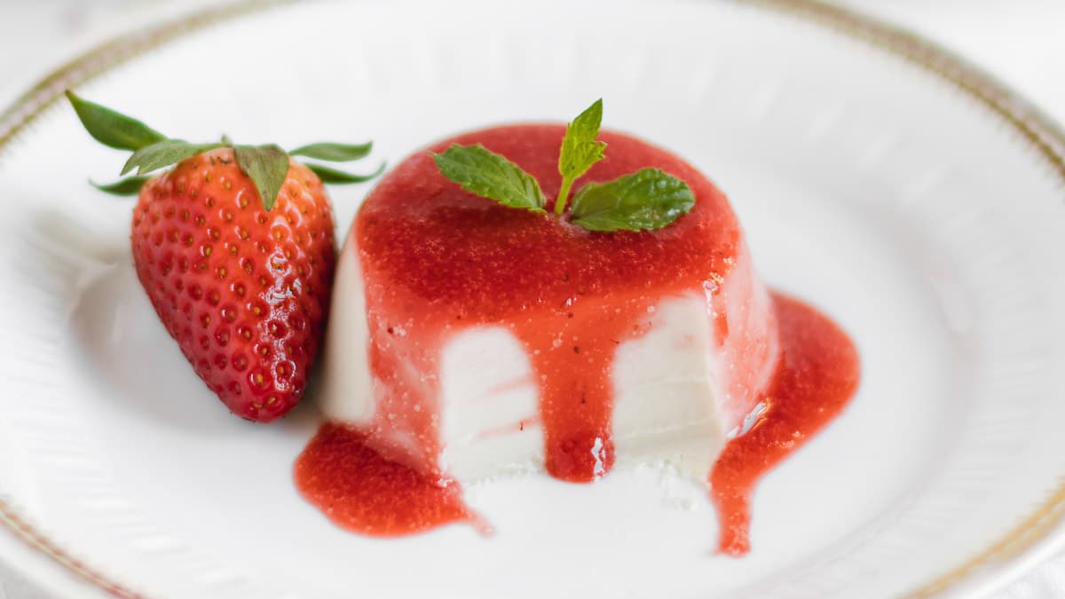 close up dairy free panna cotta with dripping strawberry sauce