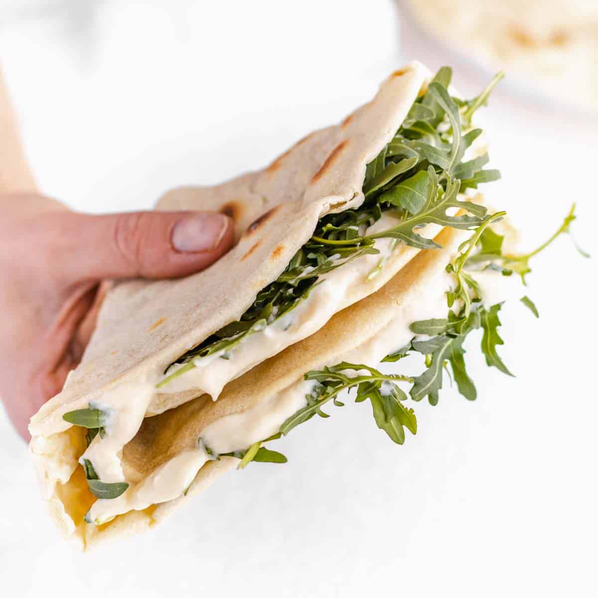 serving piadina with vegan melted cheese and arugula