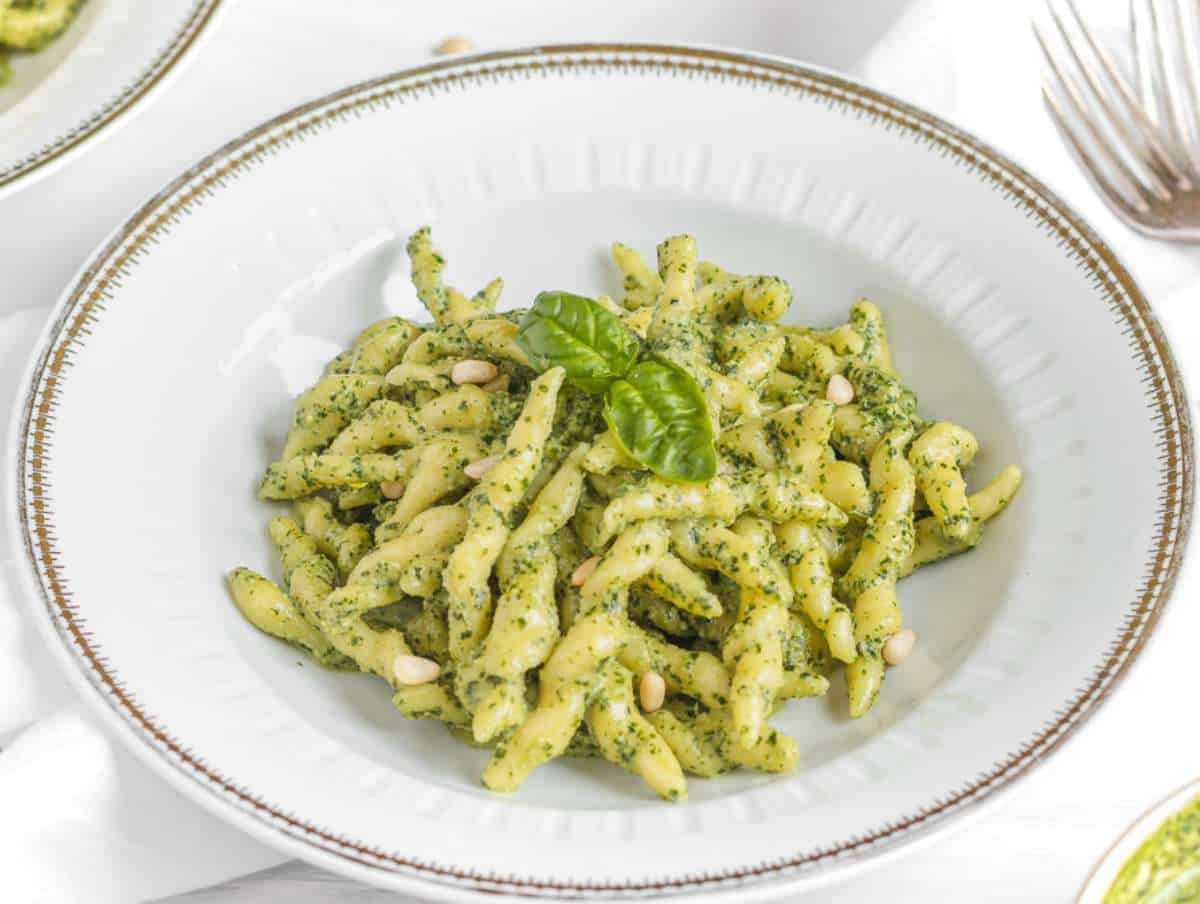 Step 5 Cooked trofie pasta tossed in basil pesto and served in a gold-rimmed pasta plate