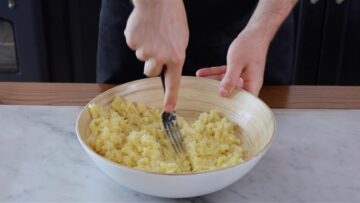 mashing the potatoes with a fork