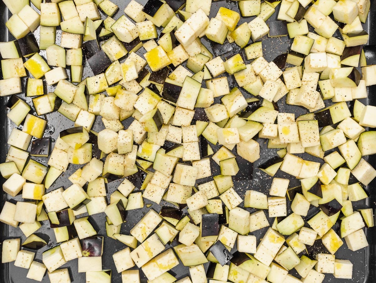 diced eggplant in a baking tray seasoned with salt, pepper and oil