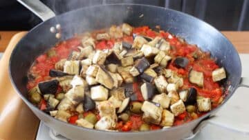 adding baked eggplants to the pan