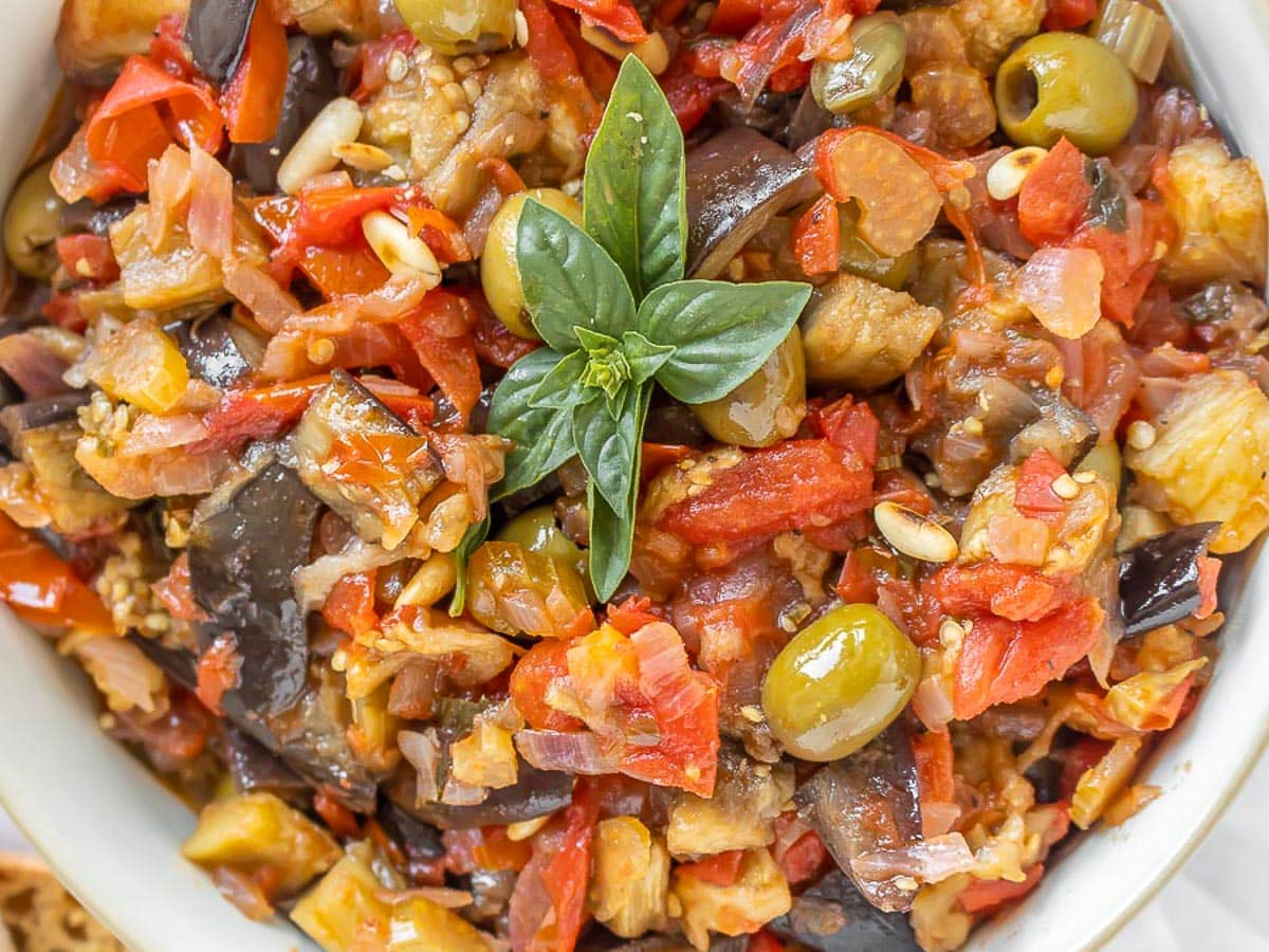 Caponata in a bowl with basil on top