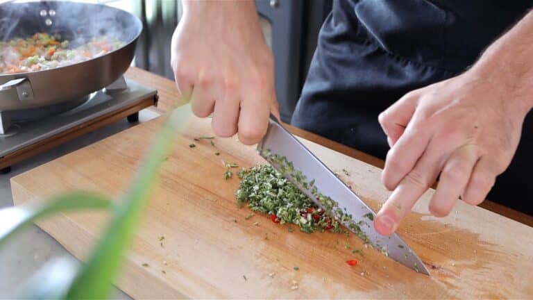 chopping sage, rosemary, garlic and chili peppers