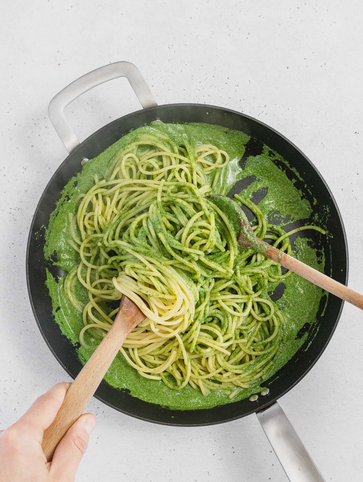 mixing the pasta with the spinach pesto