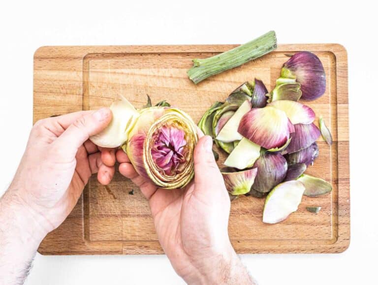 hands removing leaves from artichoke