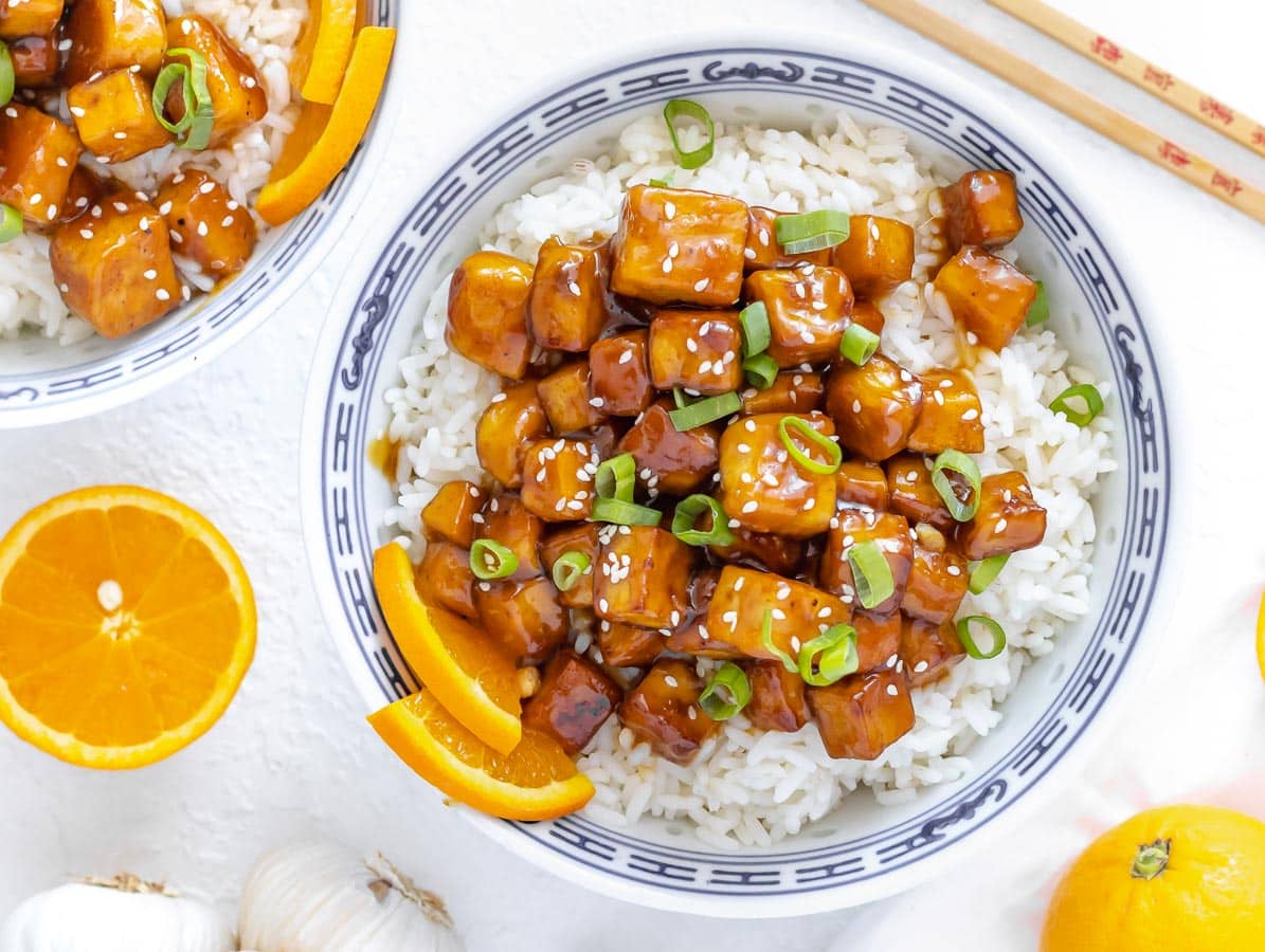 orange tofu served with rice and green onion on top