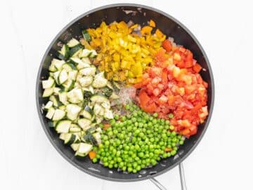 peas, pepper, zucchini and tomatoes added to the pan