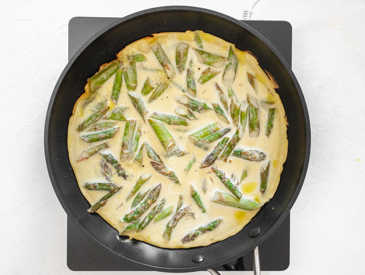 chickpea frittata with asparagus in a pan cooking