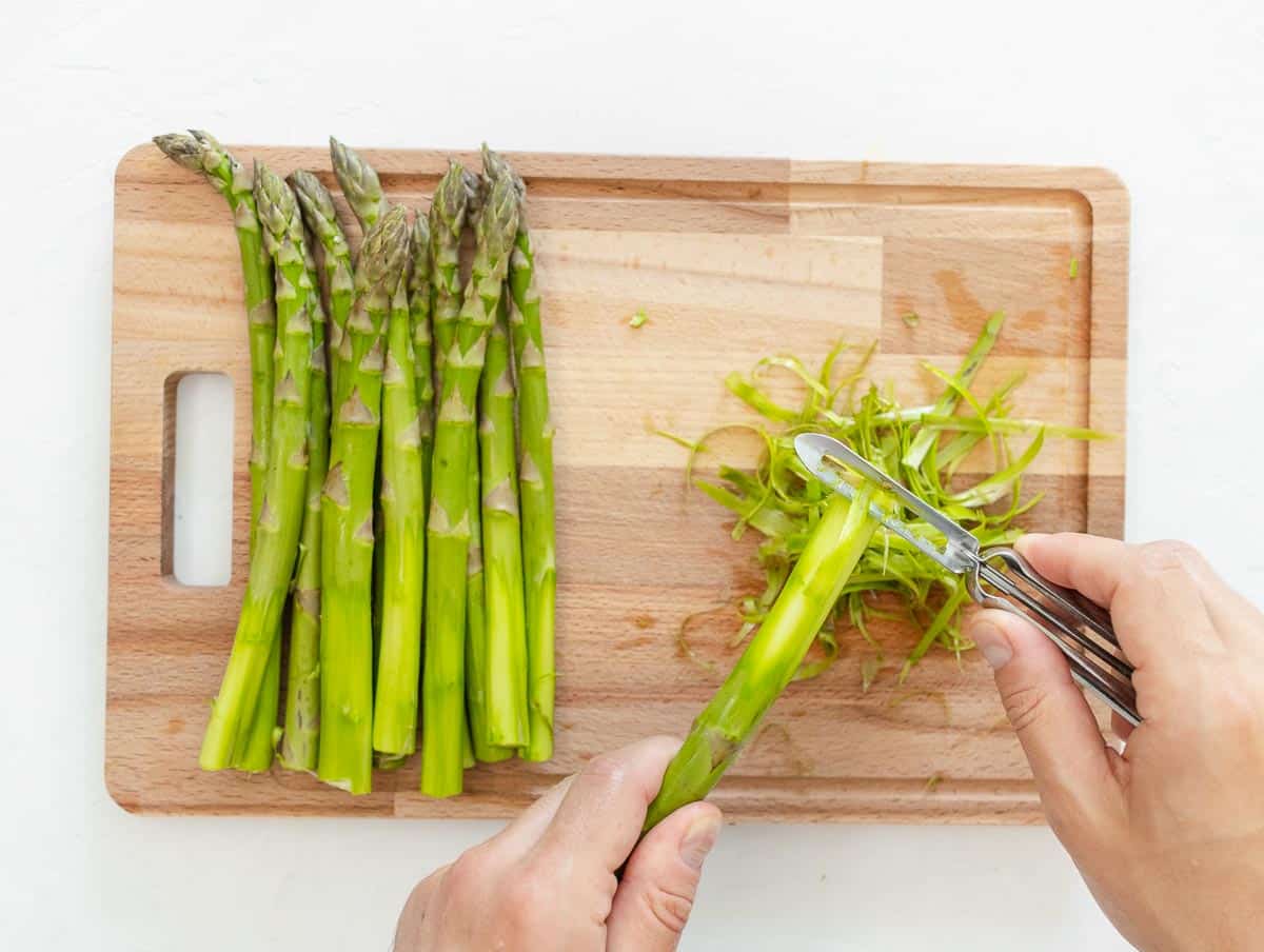peeling the stalk of the asparagus with a vegetable peeler