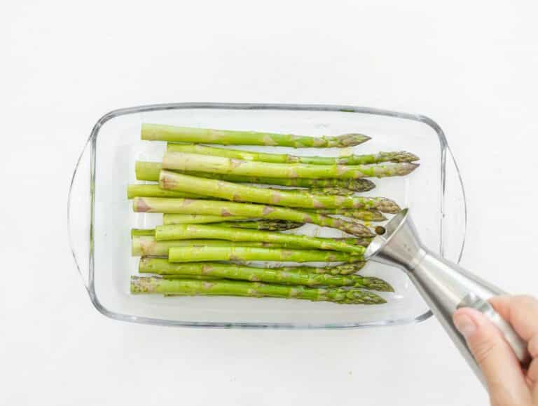 seasoning asparagus spears with olive oil, salt and pepper