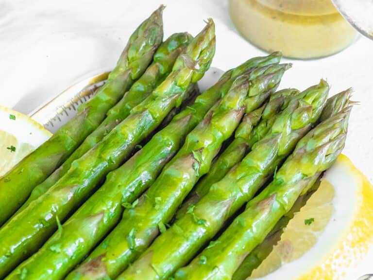 steamed asparagus served on a plate with lemon wedges