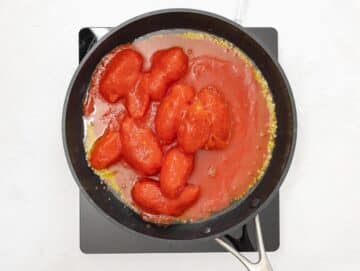 whole canned peeled tomatoes added to the pan with the garlic