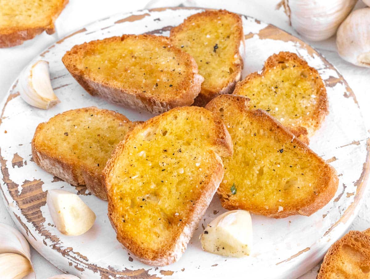 Crostini with olive oil, salt, and pepper on a white cutting board