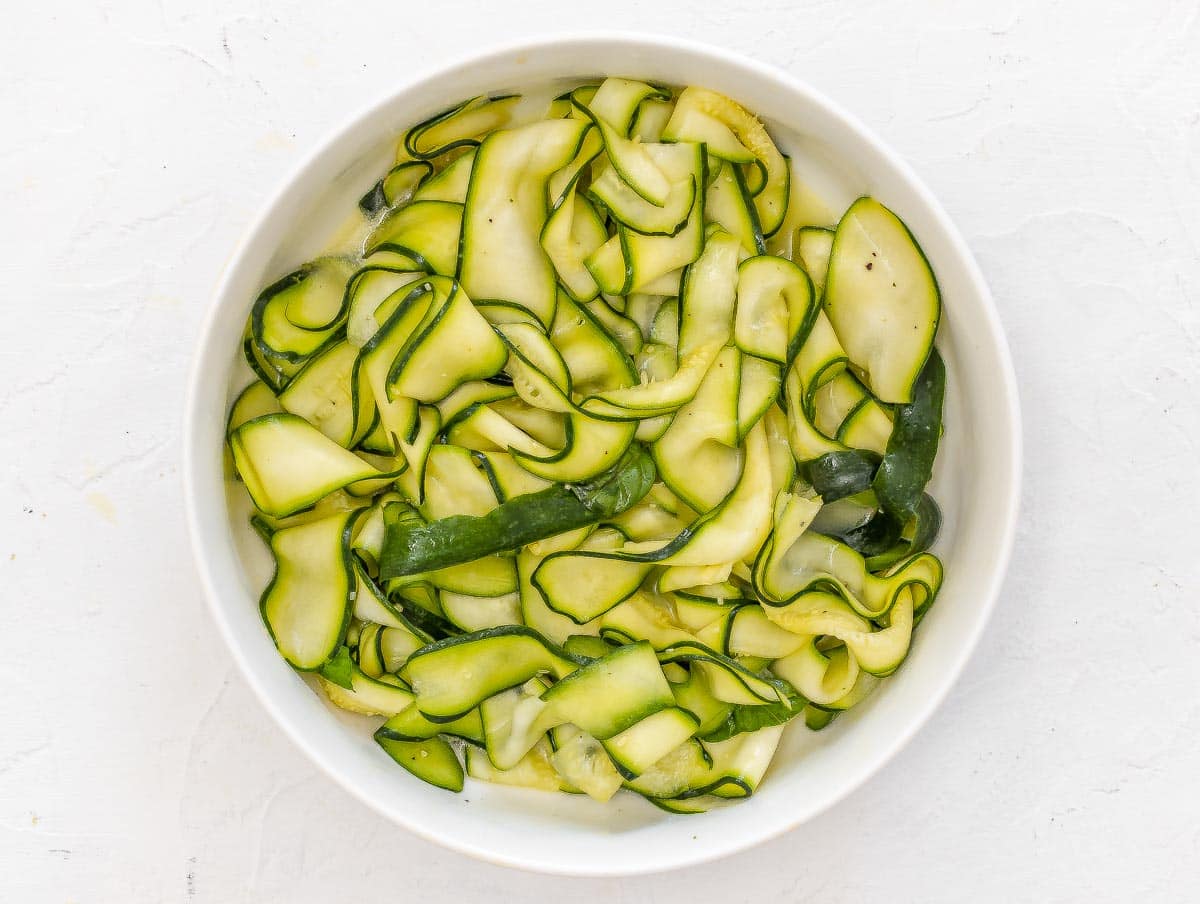 zucchini slices marinading in a bowl