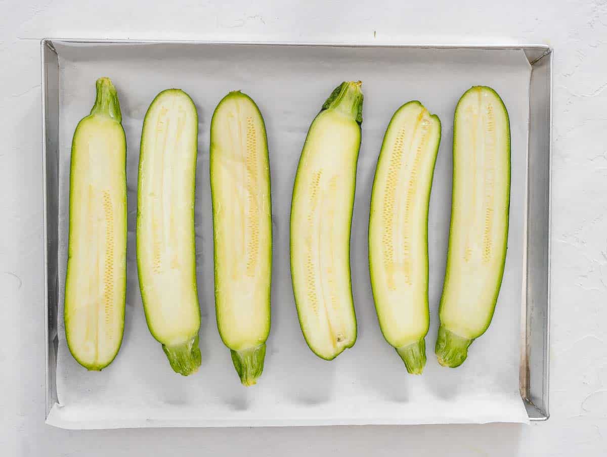 zucchini cut in half lengthwise and arranged on a baking sheet