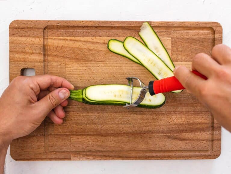 slicing the zucchini with a vegetable peeler