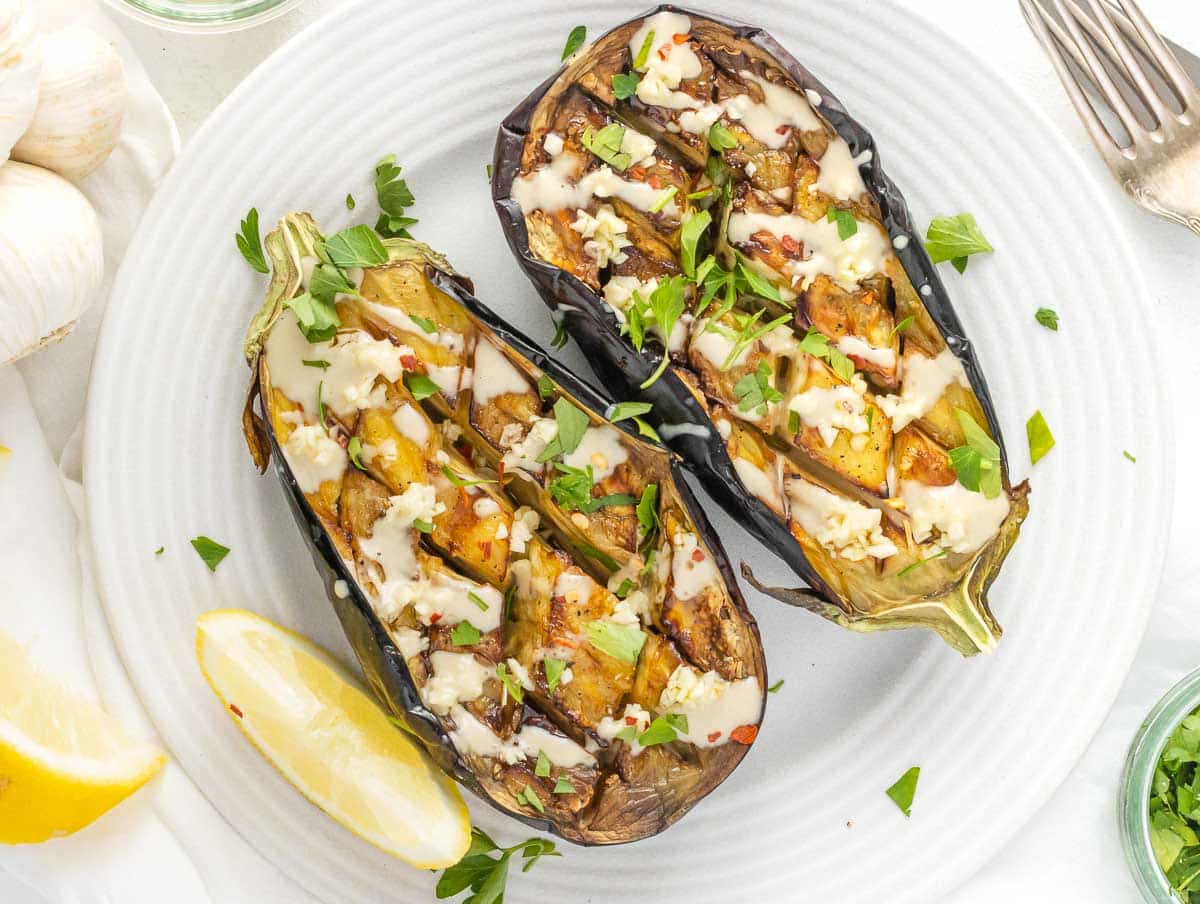 air fried eggplant boats with tahini sauce, minced garlic, and parsley