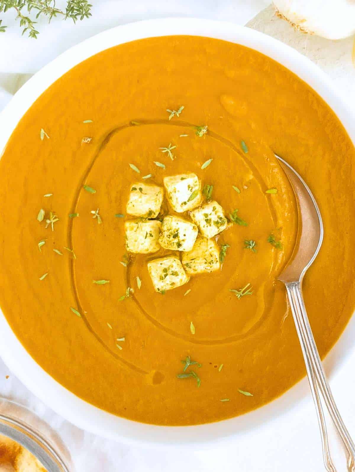 Finished soup (top down) – Bowl of roasted eggplant soup with Greek yogurt and croutons on rustic table.
