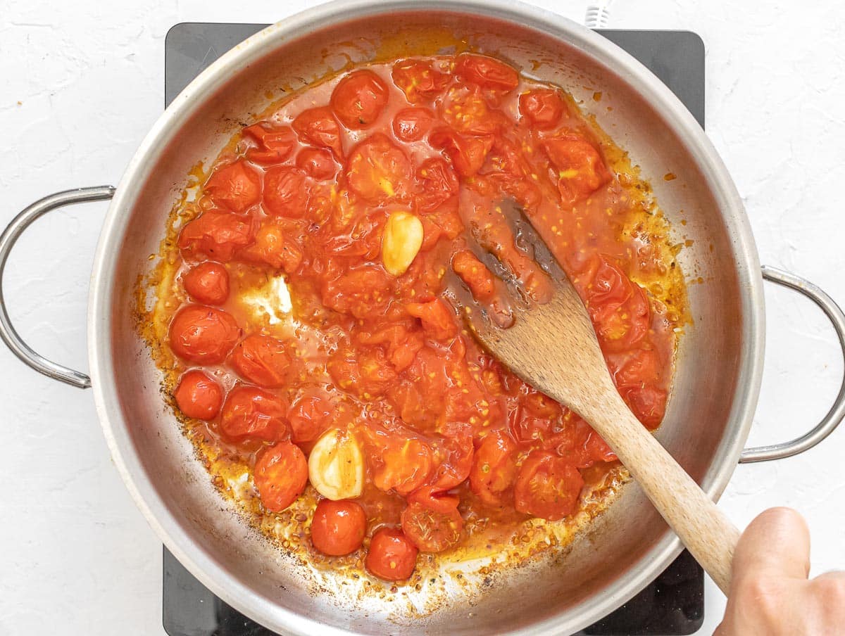 crushing fried tomatoes on pan
