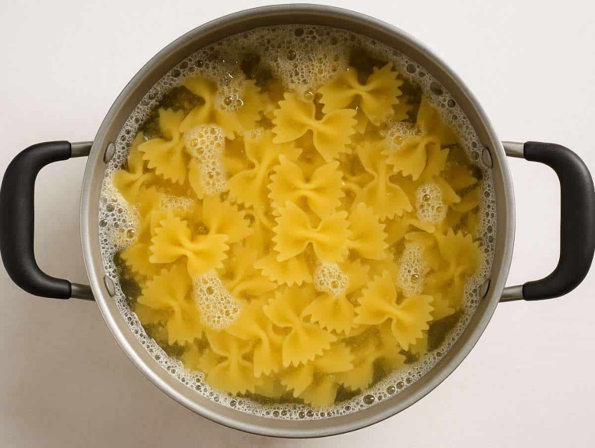 Step 2 Farfalle pasta cooking in a pot of boiling water top down kitchen view.