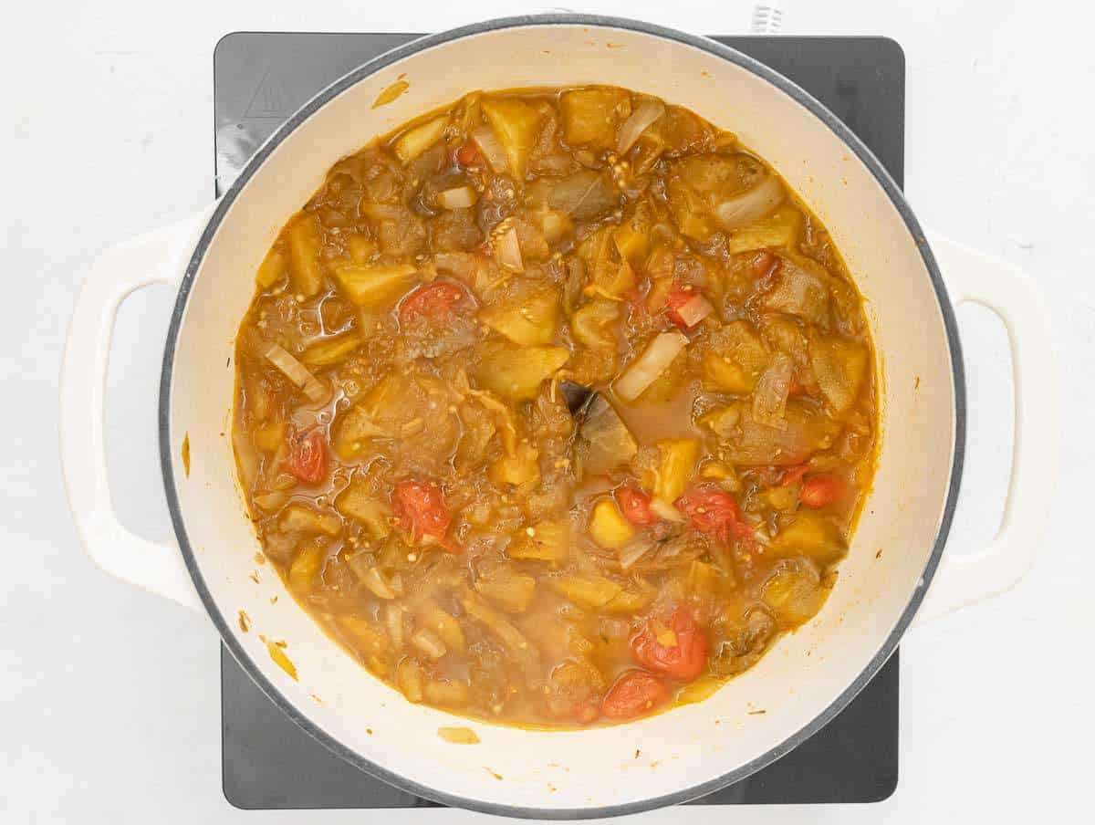 Step 2 – Adding roasted eggplant tomatoes and beans to simmering vegetable broth in pot.