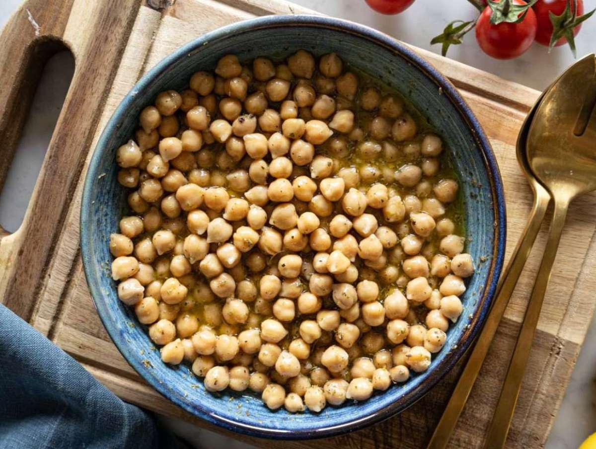 Step 4 Chickpeas marinating in dressing inside white bowl for Mediterranean roasted eggplant pasta salad.