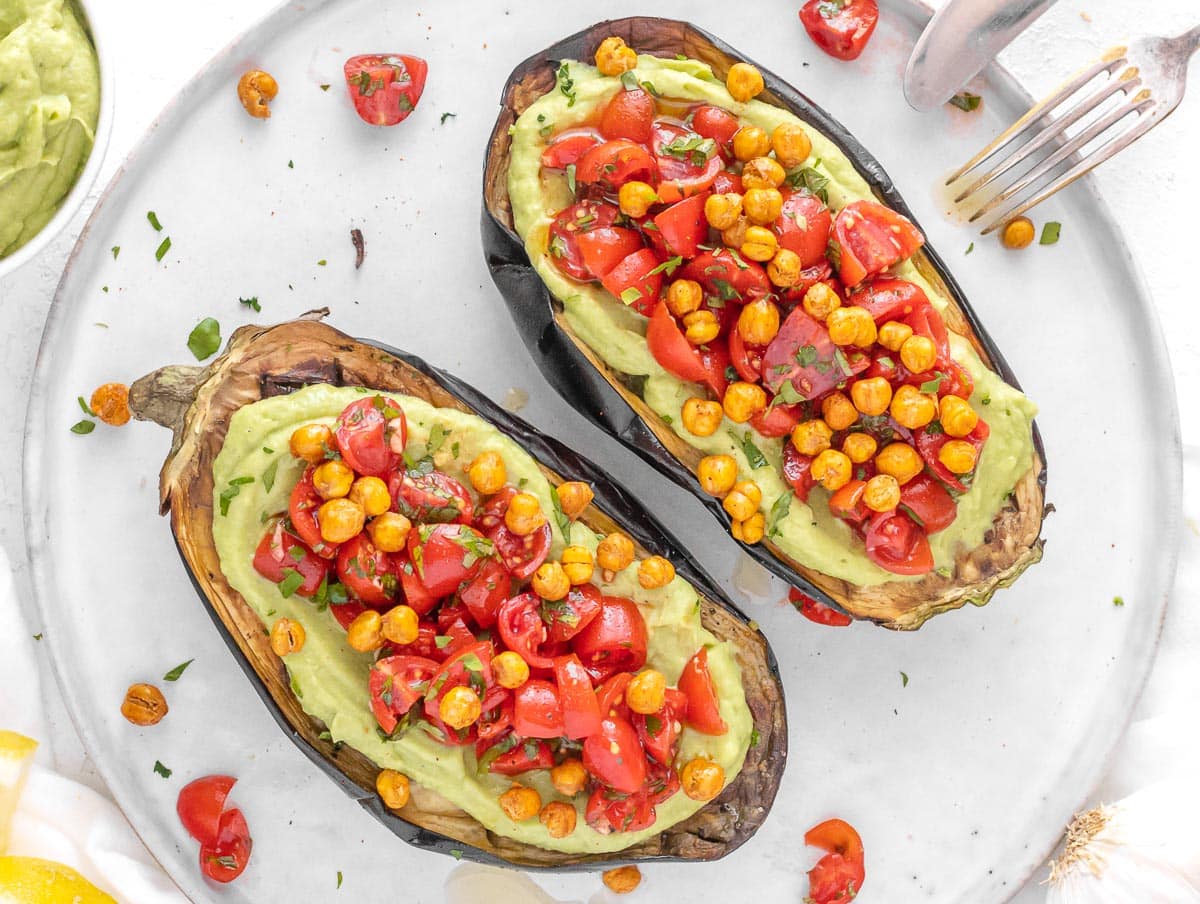 stuffed eggplant with avocado spread, tomatoes, and roasted chickpeas