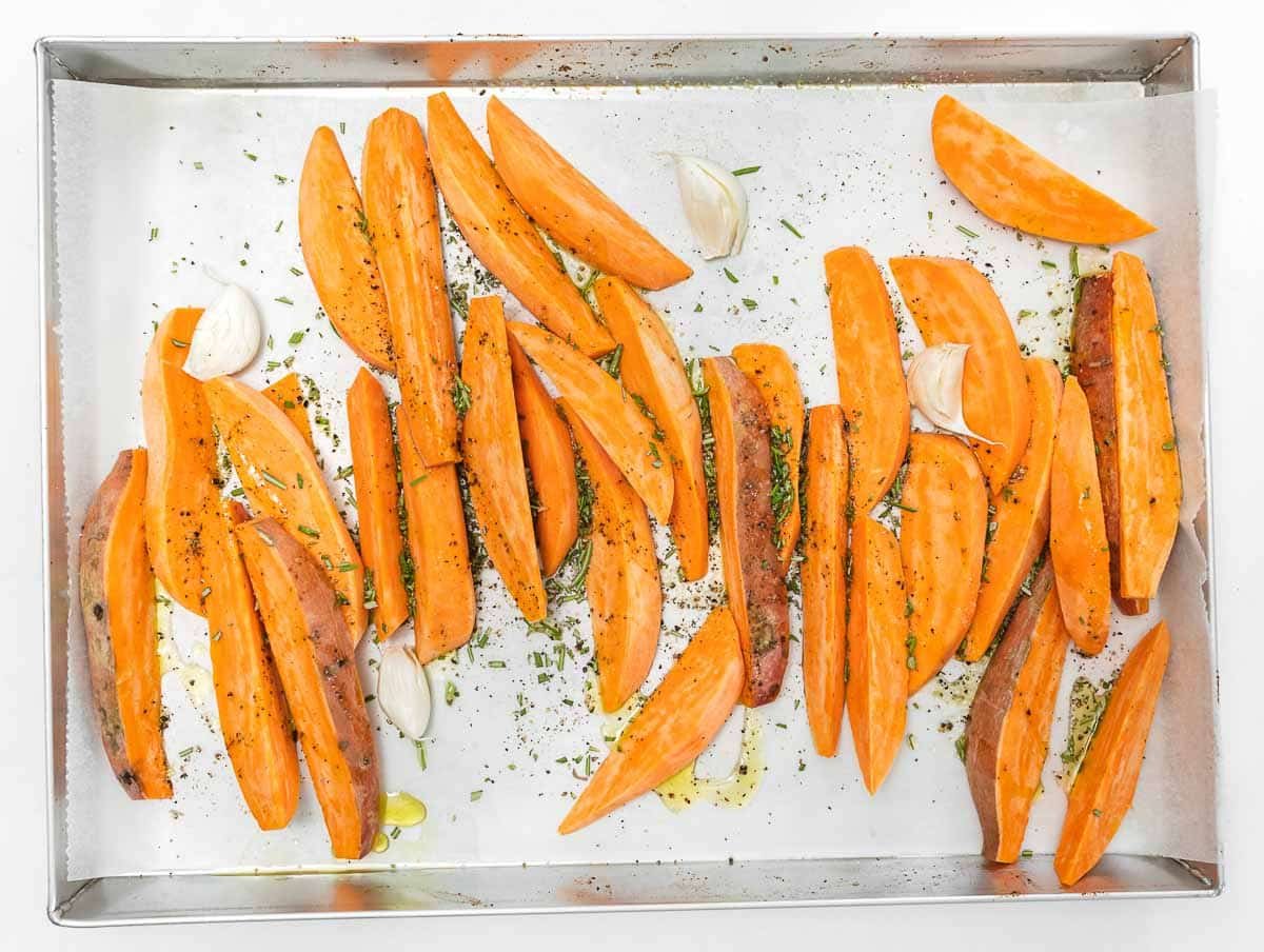 seasoning sweet potato wedges with rosemary, oil, and salt