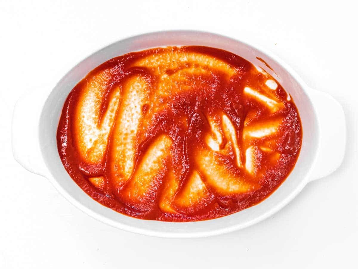 baking dish with a layer of tomato sauce