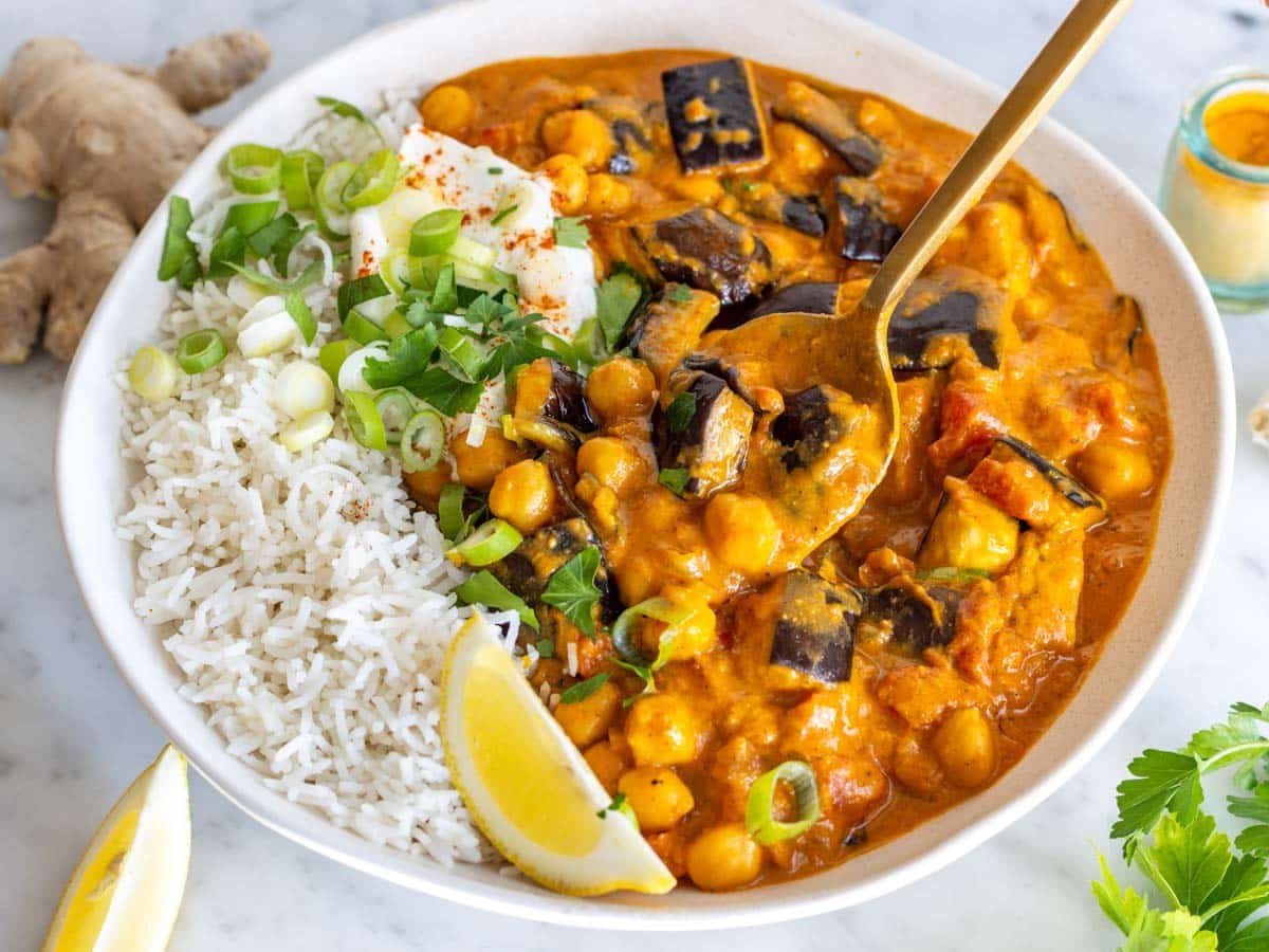 Creamy eggplant curry in a white bowl with rice.