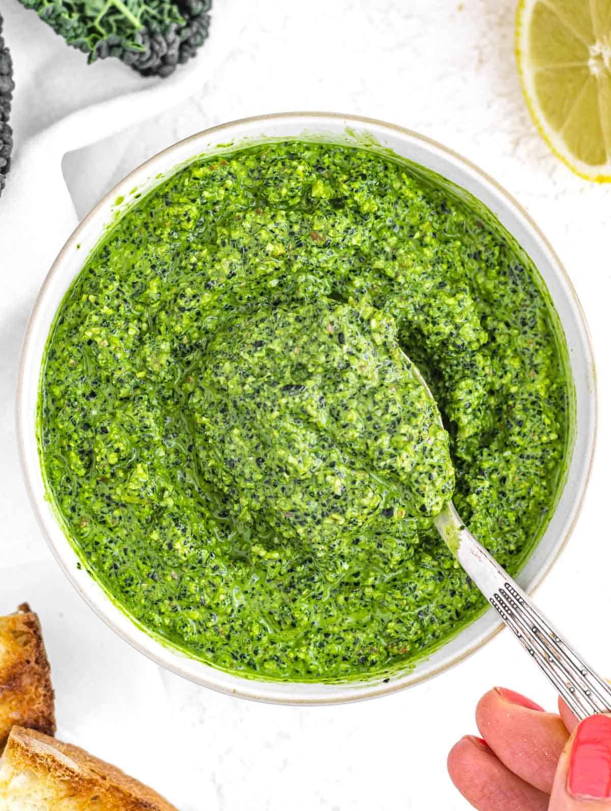 Kale pesto with hand and spoon