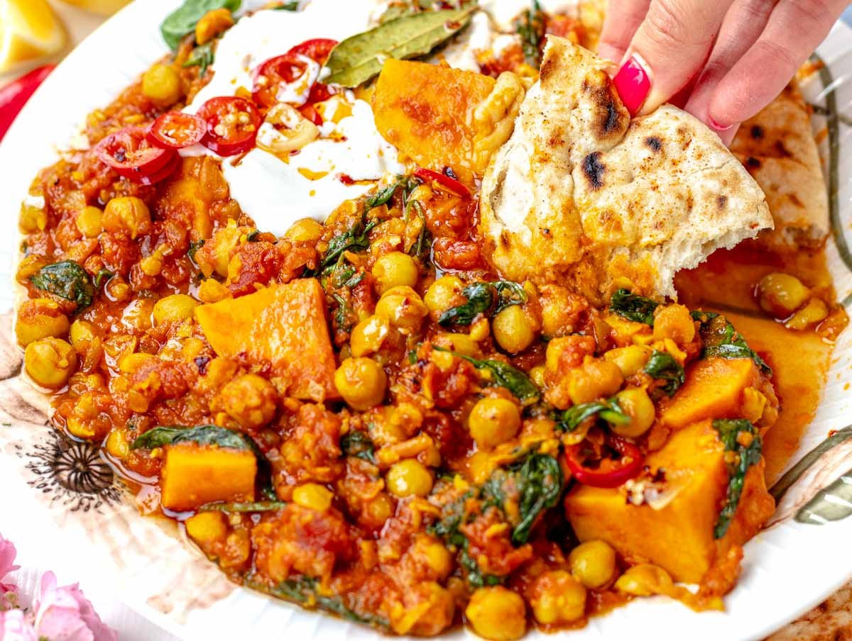 Chickpea stew and hand holding Naan bread