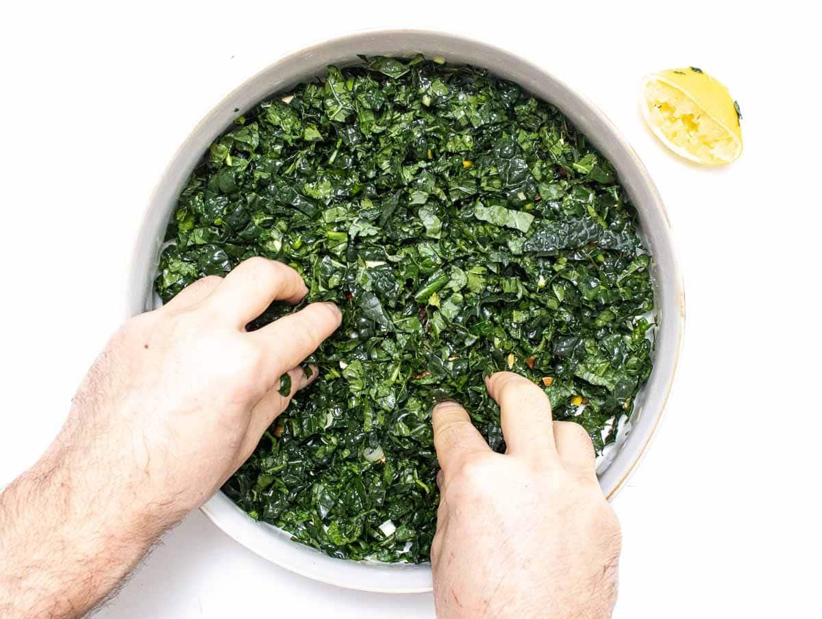 hands massage kale in a bowl