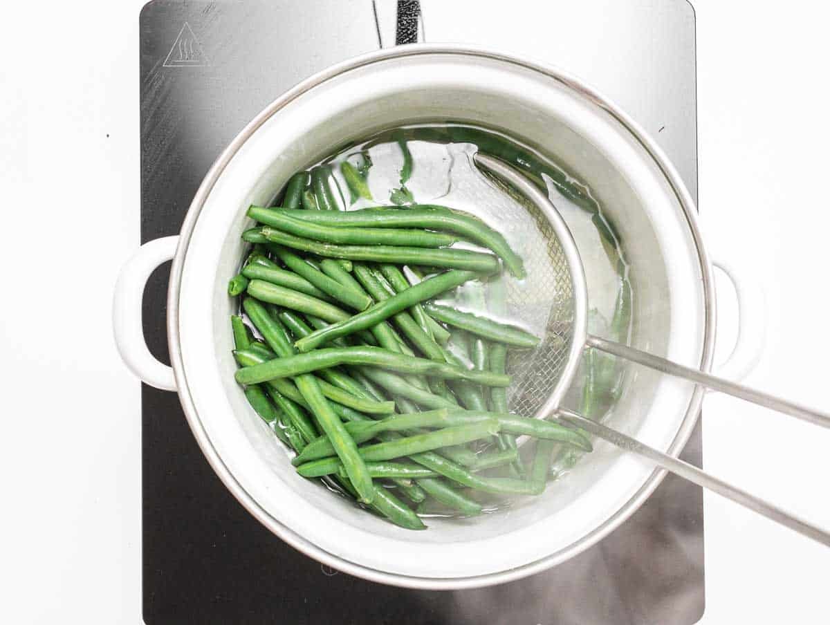 green beans boiling in a white pot
