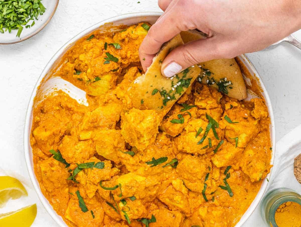 Vegan Butter Chicken with hand and bread