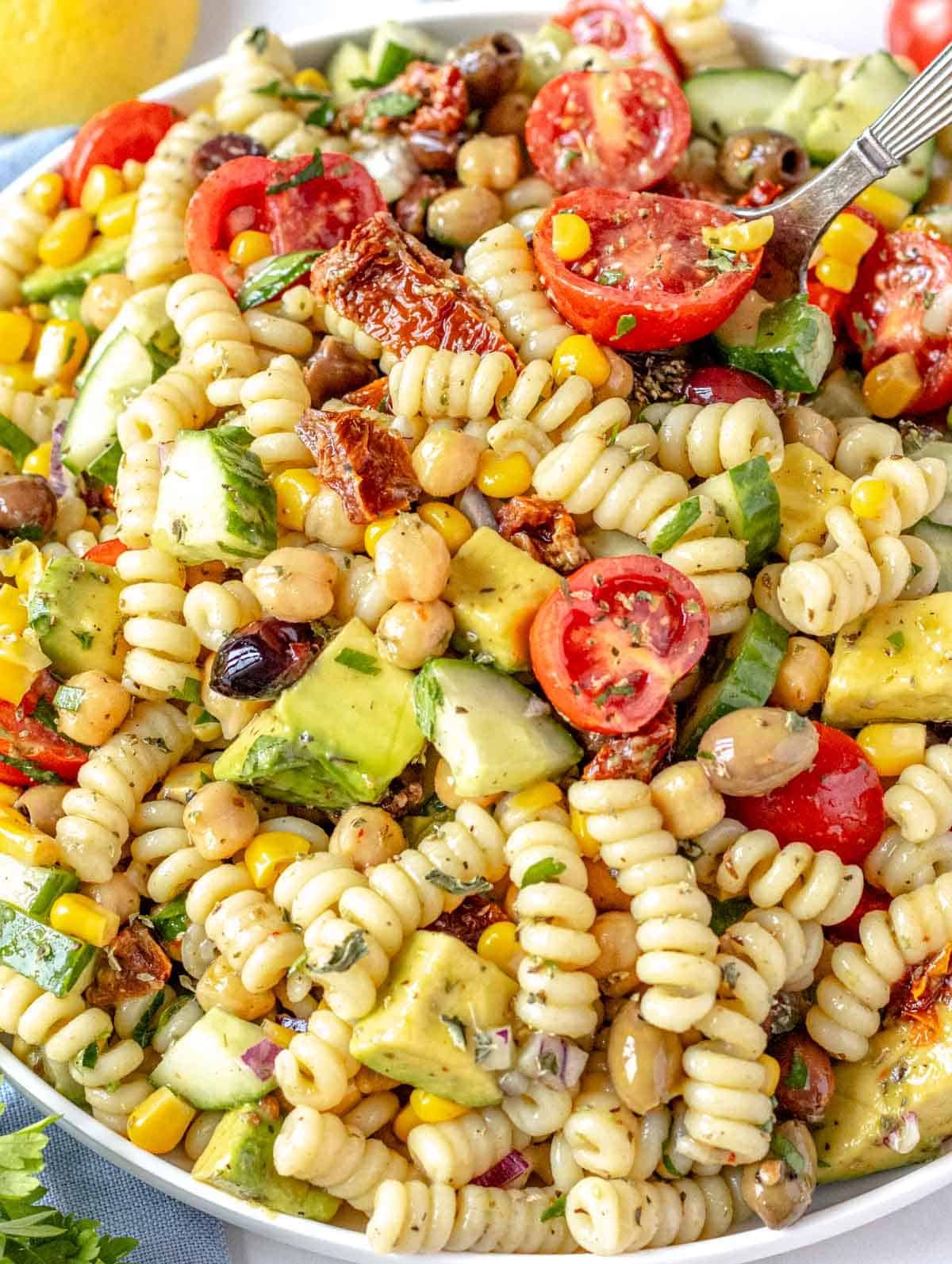 Chickpea Pasta Salad with cherry tomatoes and avocado on a white plate