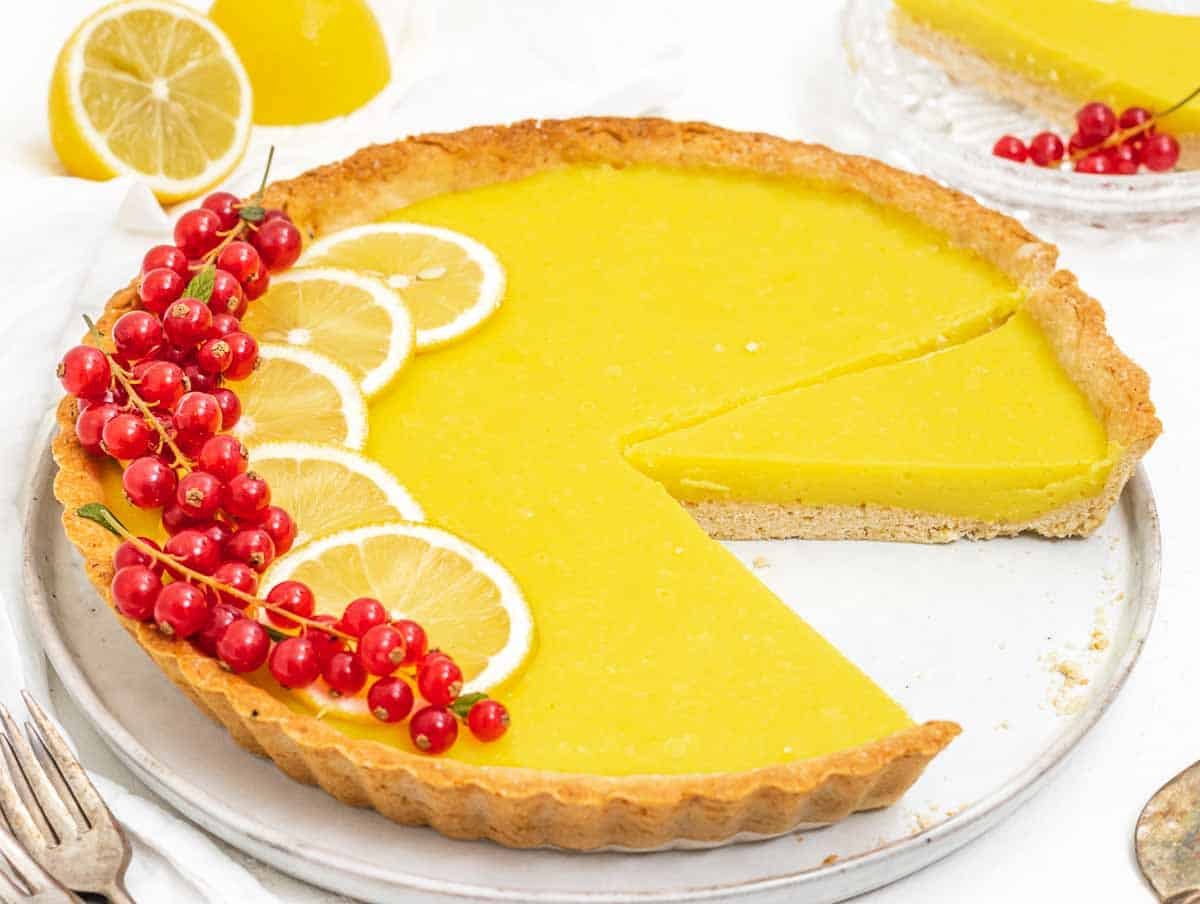 Lemon tart with slice and red berries