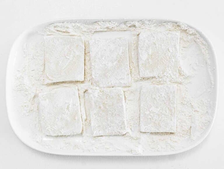 coating the tofu with flour on a plate