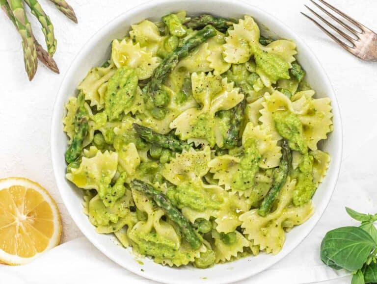 Asparagus pasta in a white bowl with lemon and basil