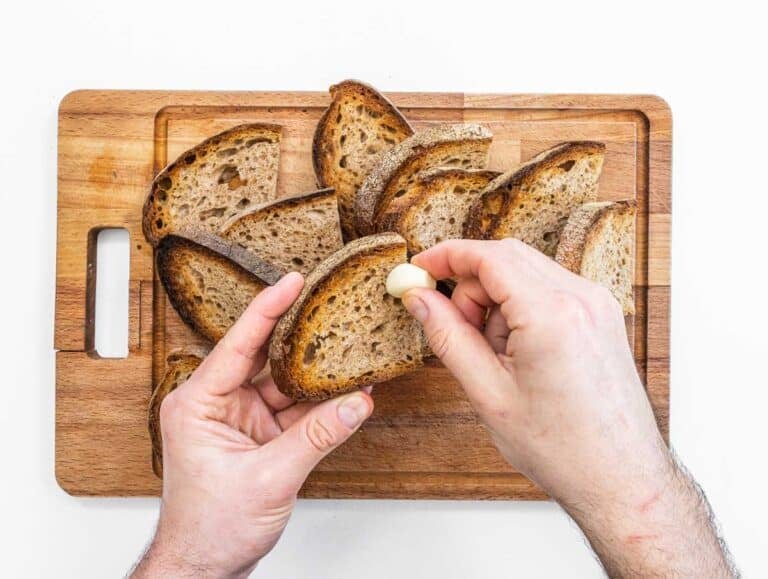 hands brushing bread with garlic