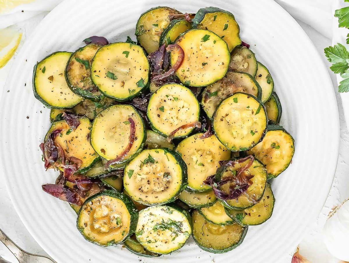 Sauteed zucchini on a white plate with a silver fork